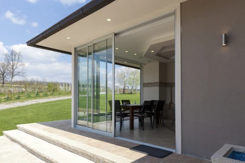 Maison contemporaine avec grande baie vitrée coulissante ouverte sur terrasse dallée