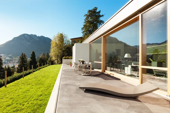 Terrasse moderne avec baie vitrée coulissante, chaise longue design et mobilier d'extérieur contemporain