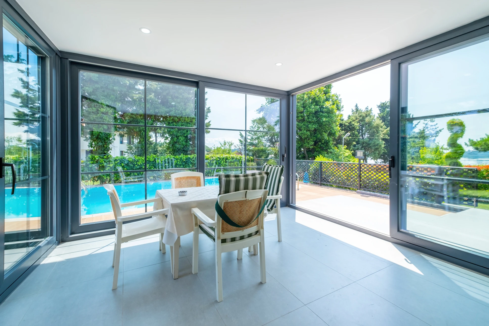 Salle à manger moderne avec baies vitrées panoramiques donnant sur terrasse et piscine