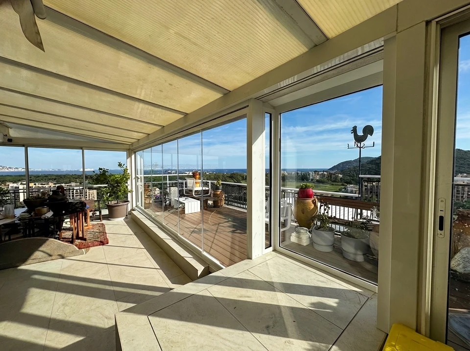 Intérieur moderne avec grande baie vitrée coulissante ouverte sur terrasse avec balustrade métallique