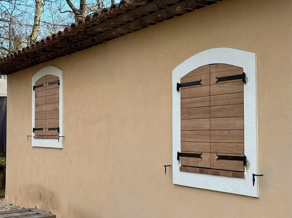 Façade extérieure de bâtiment résidentiel en briques oranges avec fenêtre équipée d'un volet roulant blanc partiellement ouvert