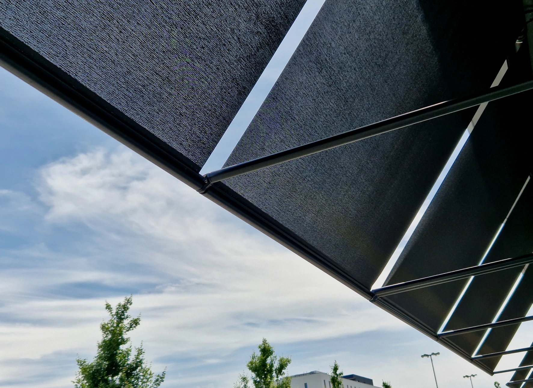 Ouvrier en salopette rouge et casquette installant ou réparant un store à lamelles métalliques sur une terrasse couverte